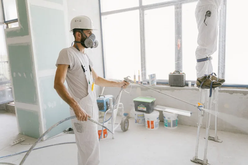 Koruyucu maske takarak sprey boya uygulayan bir usta