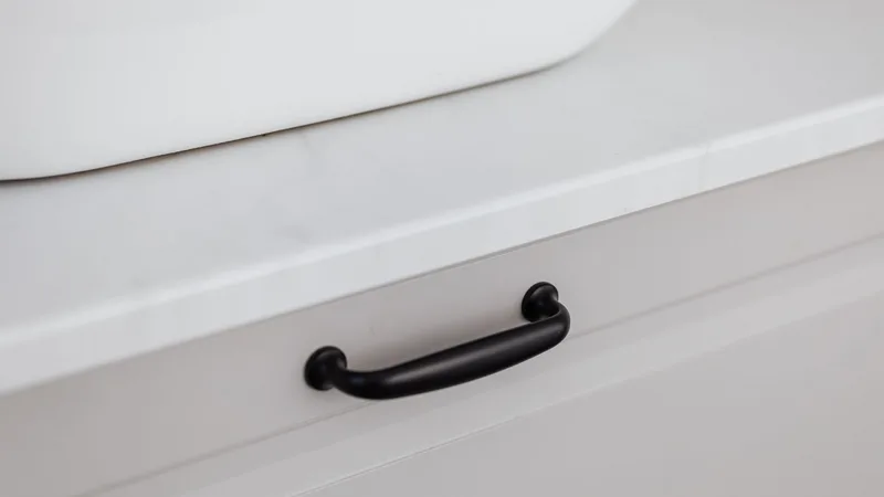 Beyaz çekmece üzerinde siyah metal kulp detayı