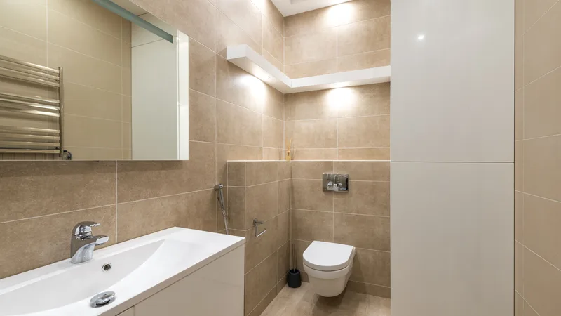 Aydınlık, beyaz ve bej tonlarında düzenli bir banyo