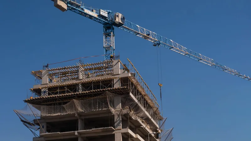 Vinçle yükselen bir kule inşaatının önünde, iskeleli beton kat kalıpları