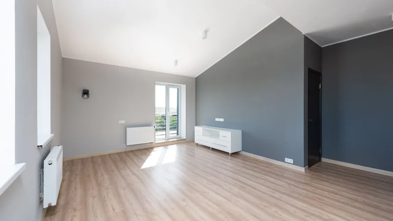 Beyaz duvarlı, ahşap zeminli, aydınlık ve boş bir yeni daire salonu