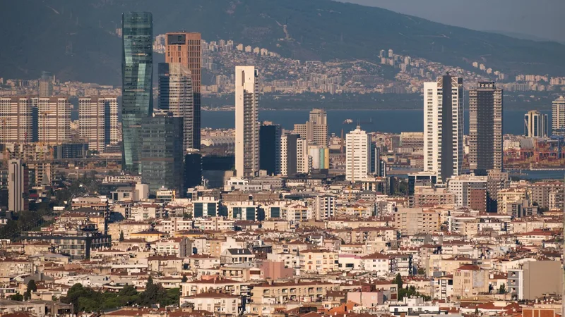 İzmir Körfezi kıyısında yükselen modern kuleler ile arka planda alçak katlı eski şehir dokusu