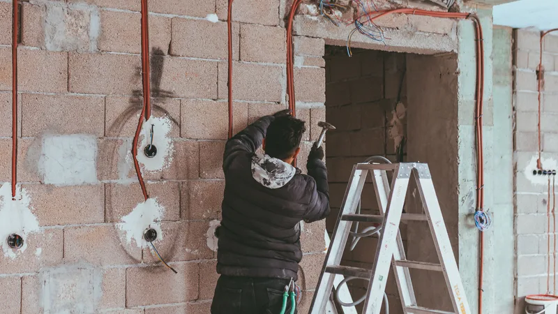 Merdiven üzerinde çalışan, tesisat borularını monte eden bir usta