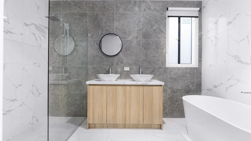 Gri mermer desenli, çift lavabolu şık bir banyo, cam duşakabin ve küvet