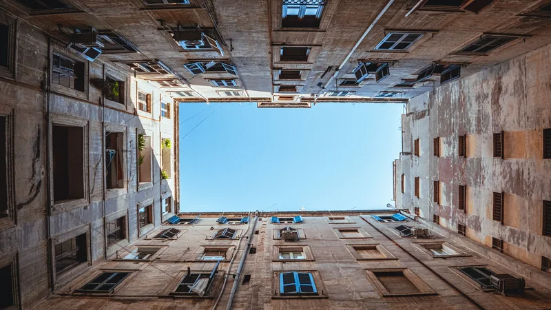 Eski bir apartman avlusundan gökyüzüne bakan geniş açı görünüm