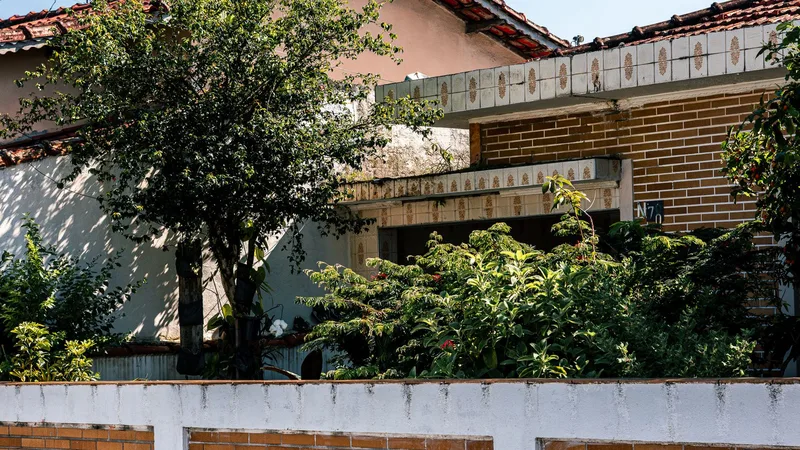 Kiremit çatılı, bahçeli ve ağaçlı bir evin tuğla duvarlı cephesi