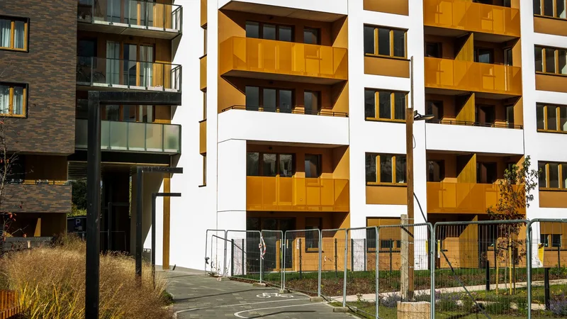 Turuncu ve beyaz cepheli, bahçeli modern bir apartman sitesi