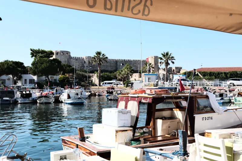 Çeşme Kalesi ve tekne limanının göründüğü sakin bir liman manzarası