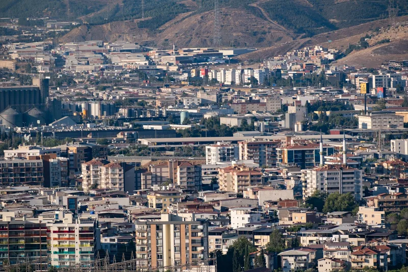 Sanayi tesisleri ve yoğun apartman dokusunun bir arada bulunduğu bir şehir manzarası
