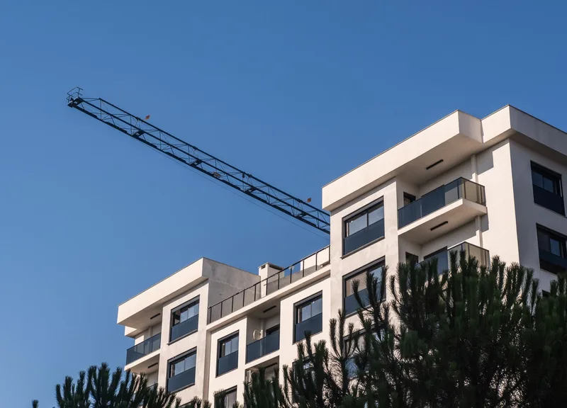 Vinç eşliğinde inşaatı süren modern bir apartman bloğu