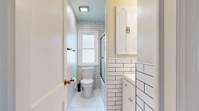 Yenilenmiş, beyaz metro fayanslı modern bir banyo koridoru