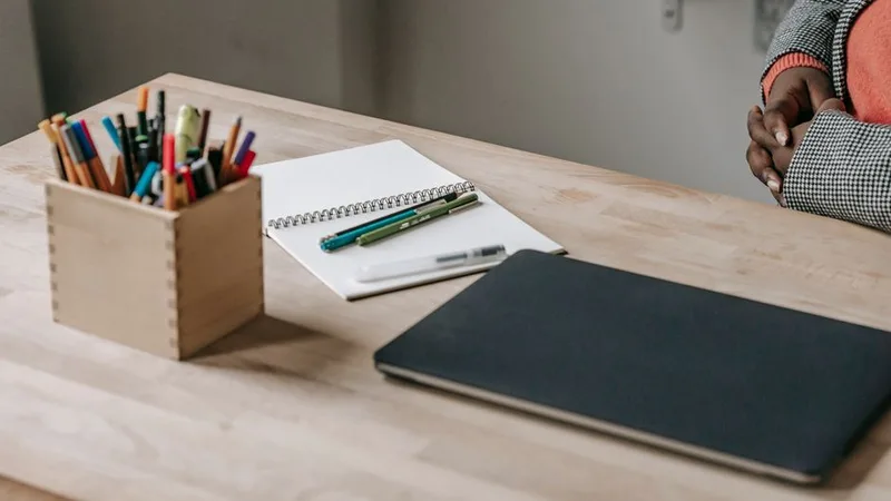 Masa üzerinde defter, kalemler ve kapalı bir dizüstü bilgisayar