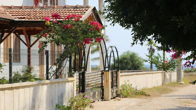 Bahçe kapısı ve demir korkuluklu, çiçekli bir yazlık villa girişi