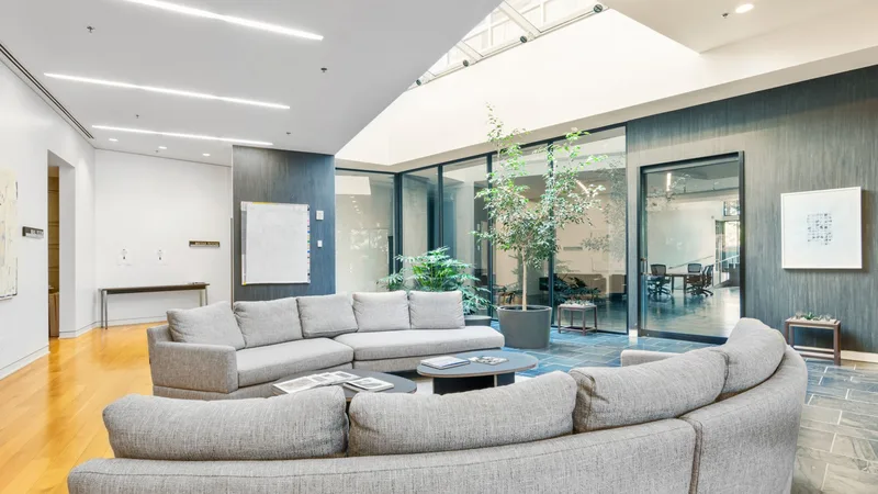 Gri kanepeli, cam bölmeli bir ofis lounge alanı
