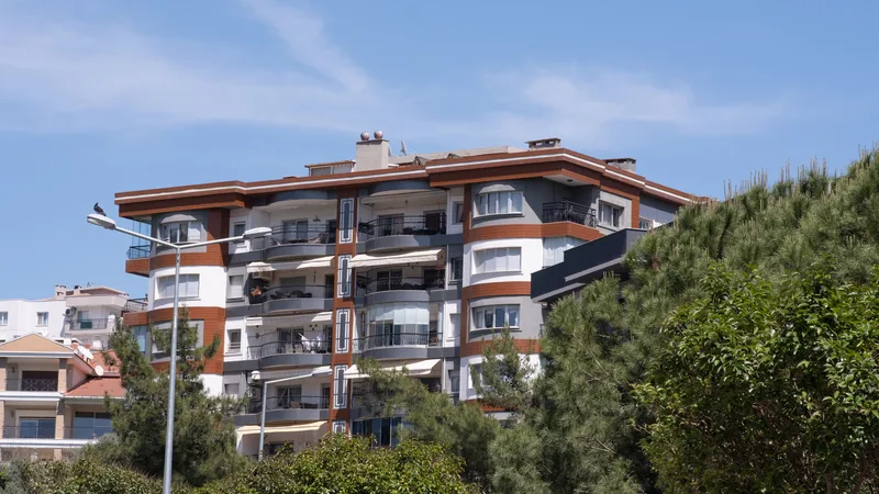 Yeşillikler arasında modern, beyaz-gri tonlu bir apartman binası