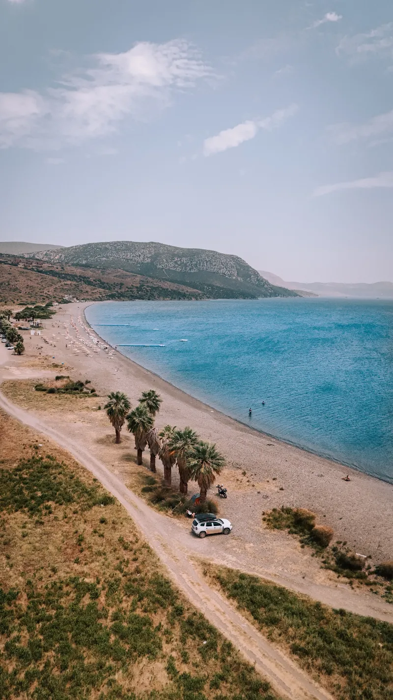 Palmiye ağaçlarıyla çevrili, dağlık kıyı şeridinde bir Karaburun koyu