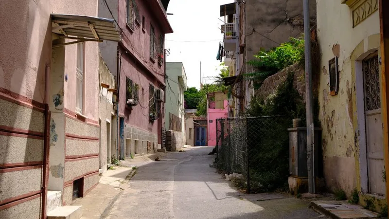 Dar bir sokakta yan yana sıralanmış, farklı renklerde eski apartmanlar