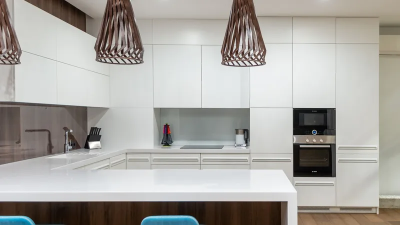 Beyaz dolaplı, sarkıt aydınlatmalı modern bir mutfak