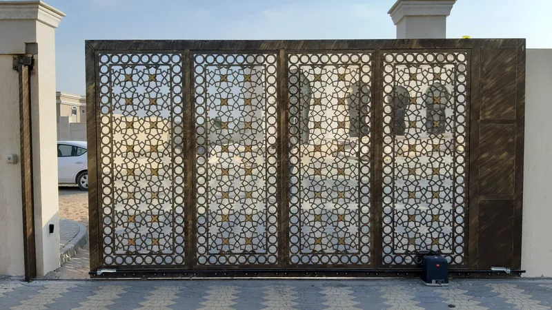 Geometrik desenli, otomatik metal sürgülü bir site giriş kapısı