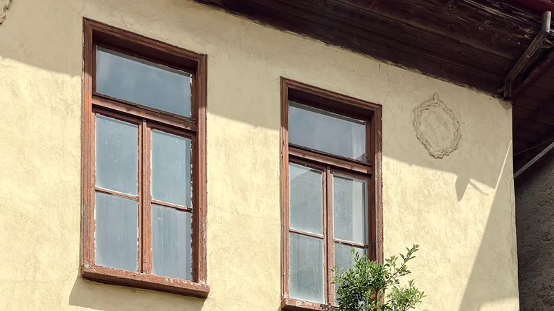 Ahşap pencereli, sıva cepheli eski bir evin dış duvarı