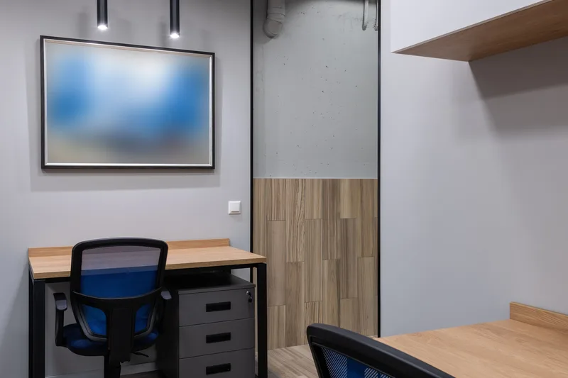 Duvarında soyut bir tablo bulunan, çalışma masalı bir ofis köşesi