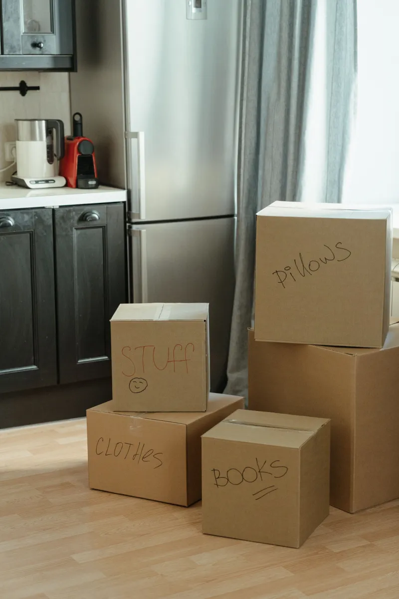 Mutfakta üzerinde 'clothes' ve 'books' yazan taşınma kutuları