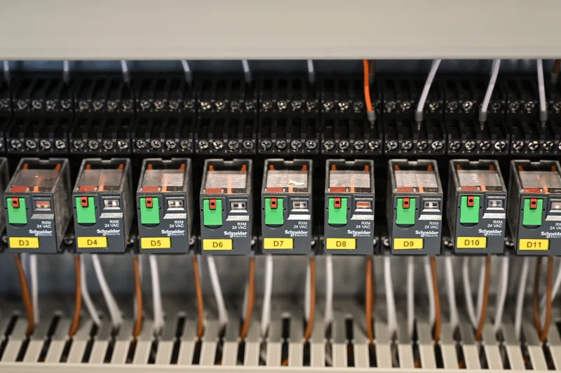 Çok sayıda sigorta ve turuncu kabloların göründüğü bir elektrik panosu