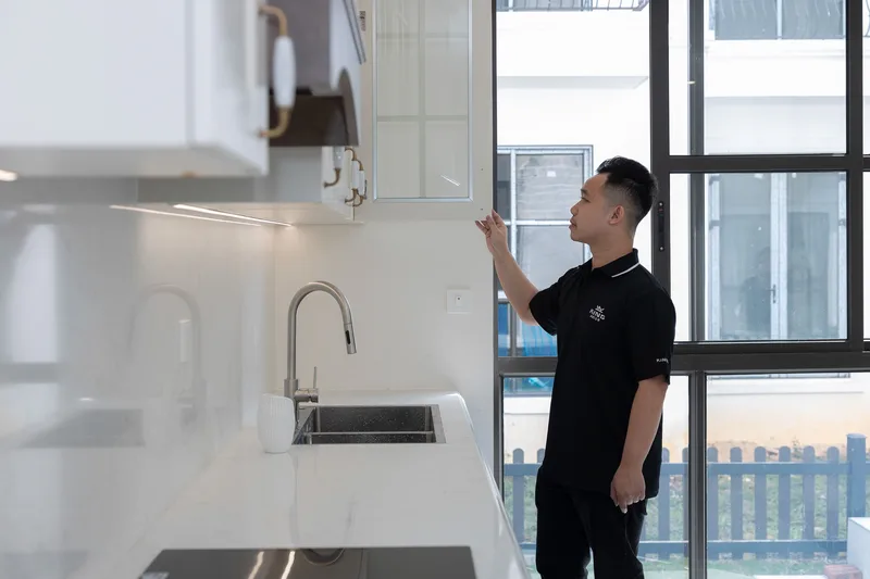 Modern bir apartman dairesinde mutfak dolabını inceleyen bir kişi
