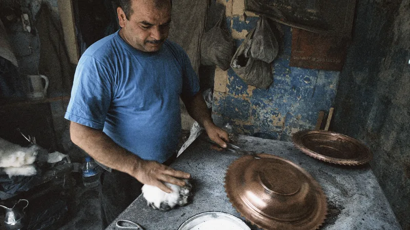 Bakır tepsiyi elleriyle cilalayan bir usta, geleneksel bir atölyede