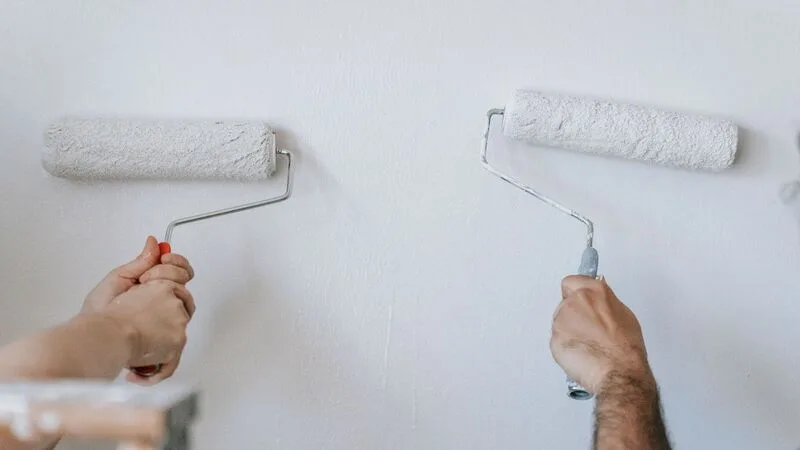 İki kişinin rulo ile beyaz bir duvarı boyaması, yakın çekim